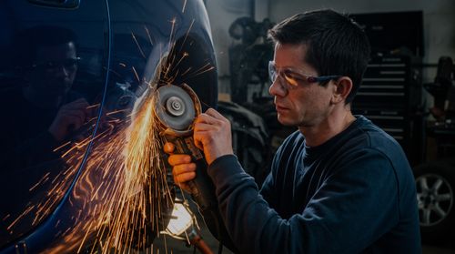 Auto body repair: technician grinding a car panel