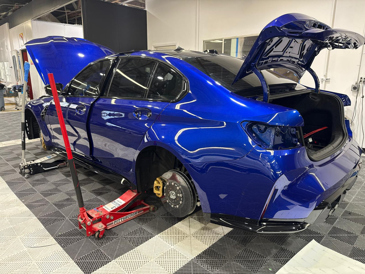 Blue BMW with rear trim and a wheel removed during work.